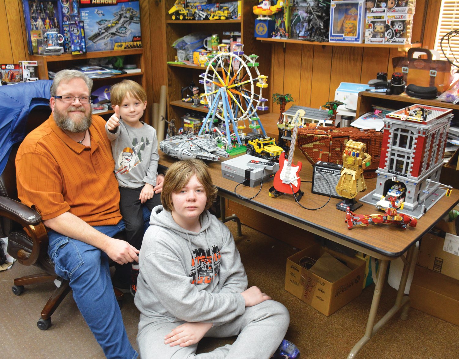 From left to right, Scott Blair, Emric Blair and Gareth Blair pose next to an assortment of LEGO builds. Building with LEGOs is beneficial for building relationships and developing spatial awareness.