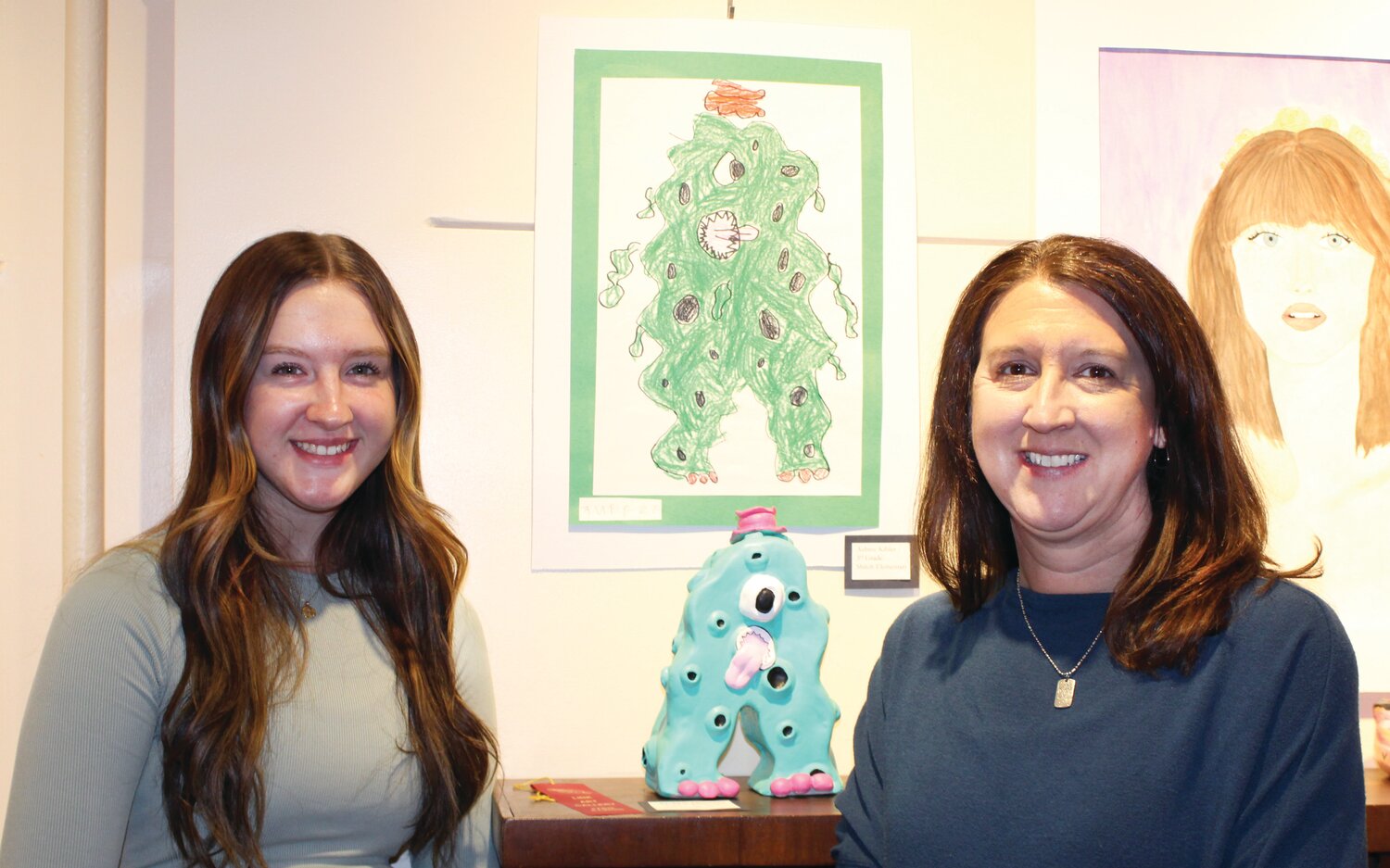 Mollie Pollock, left, received second place in the three-dimensional category in the Edgar County Student Art Show at the Link Art Gallery. Her sculpture “Blobby Monster” is in the background and based on the drawing above it created by a Shiloh elementary student. Randi Pollock, right, is Shiloh’s art teacher and her long-time practice is partnering younger students with high school artists to collaborate on projects.