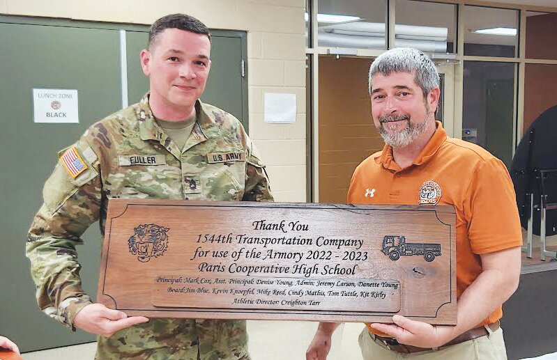 Sergeant Stephen Fuller, left, accepts a Walnut plaque made by PHS students for the 1544th Illinois National Guard from PHS principal Mark Cox, right. The plaque was in recognition of the unit helping out the high school by providing access to the gym at the armory for students to have P.E.